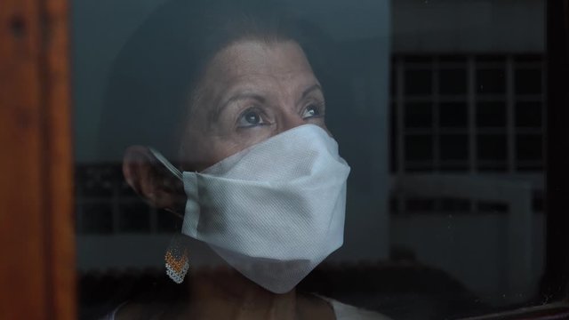 Woman in quarantine for Covid-19 looking out the window with eyes of hope