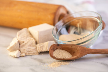 dried and fresh yeast on a white kitchen bacground with wooden rolling pin