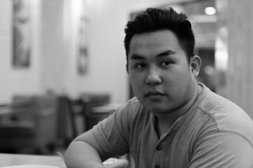 Obraz premium Face of young overweight Asian man thinking at the coffee shop