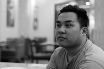 Obraz premium Face of young overweight Asian man thinking at the coffee shop