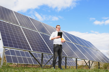 Solar energy. Young business man in a white shirt near the solar panels to power plants.