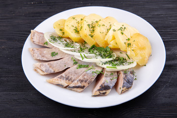 Herring in oil, with cooked potatoes, onions and greens