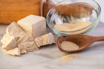 dried and fresh yeast on a white kitchen bacground with wooden rolling pin