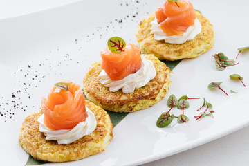 Red salmon fish is folded and lies on potato pancakes.
