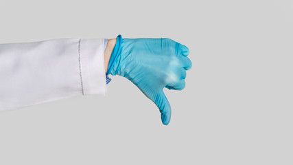 Hand in medical glove shows dislike sign