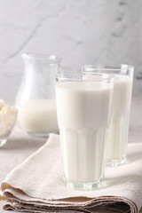 Kefir or Ayran fermented drink in a glasses and jug, as well as cottage cheese in a bowl on light gray background, Vertical format