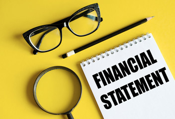 Financial Statement text written on a notebook with pencils glasses magnifier