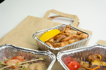 Lunch and dinner with home delivery in foil boxes and paper bag on a white background.