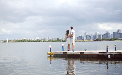 Fototapeta na wymiar Lovers stand on the pier and look at the lake and the city, lovers relax