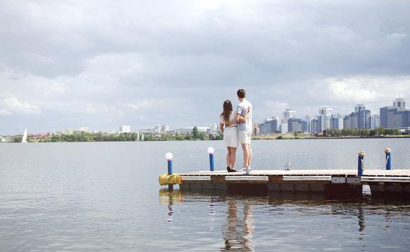 Lovers stand on the pier and look at the lake and the city, lovers relax
