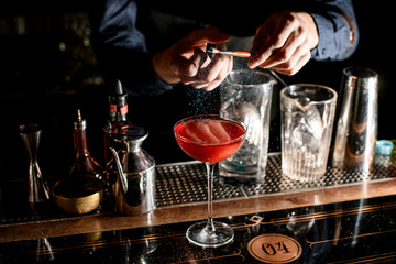 Fototapeta na wymiar male bartender decorates glass with colored sugar using brush.
