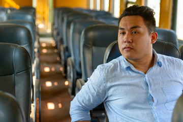 Young overweight Asian tourist man riding inside the train