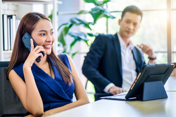 Beautiful young Asian Business woman calling phone while meeting at office. Teamwork meeting and partnership conference working concept.