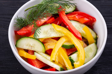 Salad of fresh cucumbers, tomatoes and Bulgarian pepper with greens