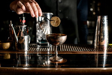 Fototapeta na wymiar bartender decorates beautiful metal glass with slice of citrus