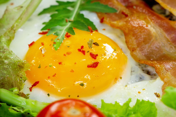 Fried egg with bacon, vegetables and herbs in frying pan. Keto breakfast for keto diet.