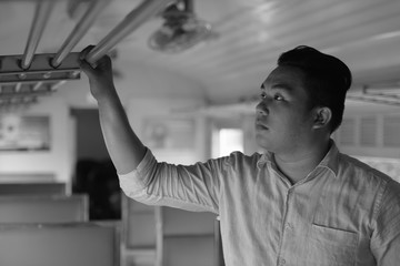 Young overweight Asian tourist man riding the train in black and white