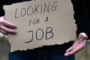 the unemployed person holds in his hand the cardboard tablet with the inscription looking for a job...