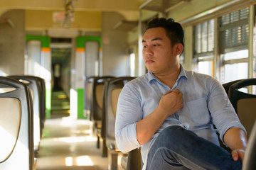 Young overweight Asian tourist man inside the train