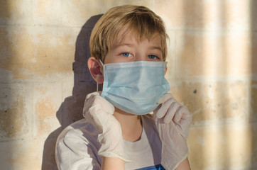 A child with a medical face mask and latex gloves. Protecting the child from Coronavirus and other respiratory diseases. Young children use medical face masks and gloves to protect their health.