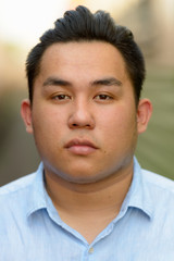 Face of young overweight Asian tourist man at railway train station