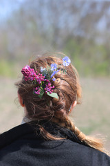 Naklejka premium wildflowers in girl’s hair against the background of nature.