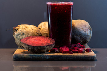 Glass with beet juice (Beta vulgaris) and tubers on wooden board © Alex R. Brondani