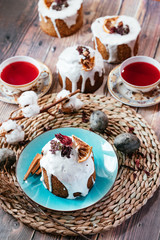 Still life. Easter cake in a blue plate on a wicker stand. Tea mugs and easter eggs. On a wooden background. Top view.