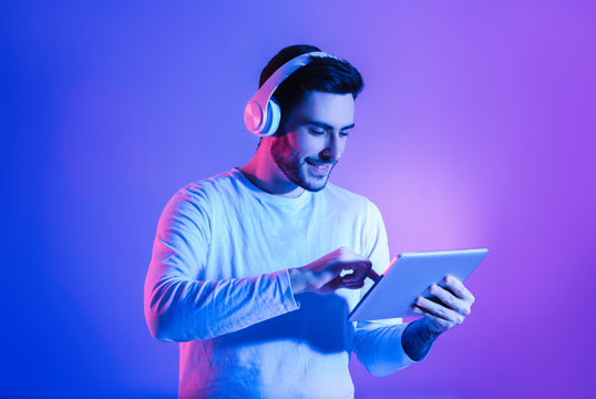 Happy man in wireless headphones uses tablet