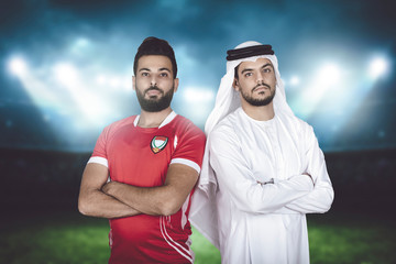 tow Emirati guys player and his manager with crossed arms standing inside stadium in UAE.