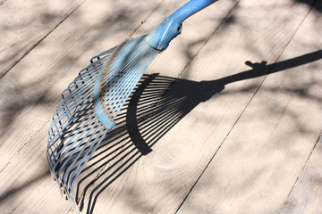 Blue fan rake and their shadow on the floor of wooden boards