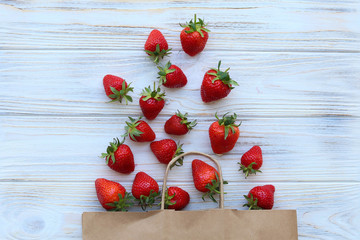 Fresh strawberries fell on the table from the eco packet, top view