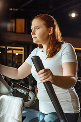 confident overweight girl training on stepper in sports center