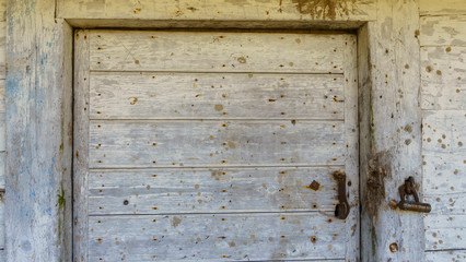 Rustic barn white door. Wooden planks and locks closeup. Peeling paint and weathered. Space for text. Texture and background.