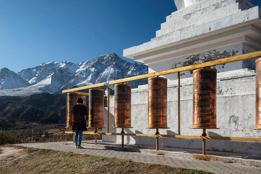 Female Tourist and White Buddhist Stupa and Tibetan prayer wheels at Mati Temple Scenic Area, Zhangye, Gansu Province, China