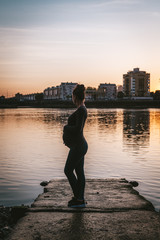 Fototapeta premium Pregnant woman enjoying sunset by the river