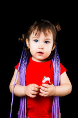 A little girl on a black background with Afro-pigtails, artificial plaited in elastic bands and put on