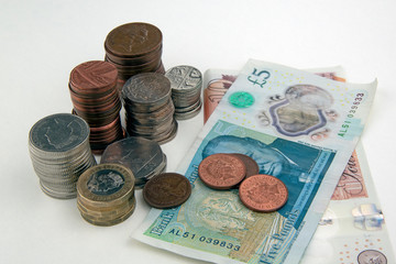Piles of coins and some British bank notes on white
