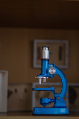 blue microscope stands on a shelf of a training cabinet