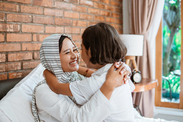 happy muslim mother cuddling with her daughter on the bed