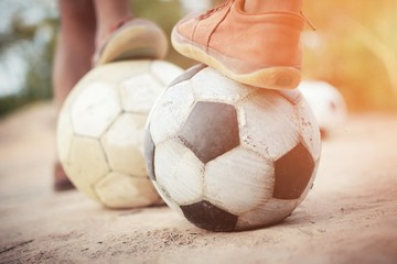 the boy's legs playing football on ground with fun in vintage style. Concept for young activity...