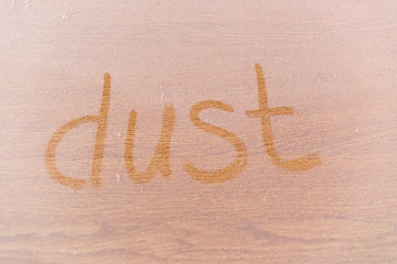 Dust written on dusty wooden surface