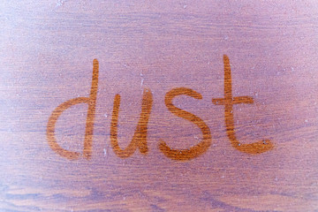 Dust written on dusty wooden surface