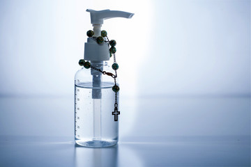 Coronavirus prevention , Bottle of hand sanitizer alcohol gel With a Wood rosary - Grey background 1
