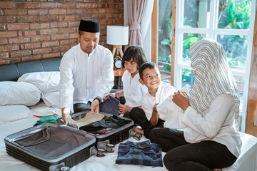 asian family prepare clothes and put in suitcase for carried when mudik go to back village home