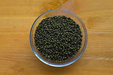 green mung beans in a glass bowl on yellow wooden table. top view. Healthy lifestyle.