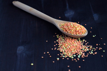 red lentils in wooden spoon. different kinds of lentils on a wooden table. Healthy lifestyle. close-up red and yellow lentils in a wooden spoon on a black background. copy space