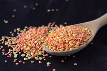 wooden spoon with different kinds of lentils on a wooden table. Healthy lifestyle. close-up red and yellow lentils in a wooden spoon on a black background. copy space