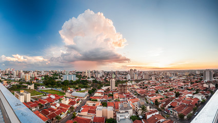 Panorama of Bauru city with houses, buildings, parks and a giant cloud at sunset