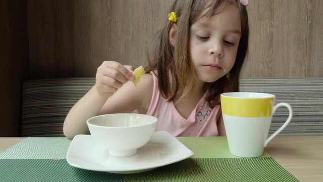 Beautiful cute little child, baby gerl, drink tea. Kid having breakfast.